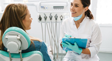 Dentist smiling at patient while taking notes on clipboard