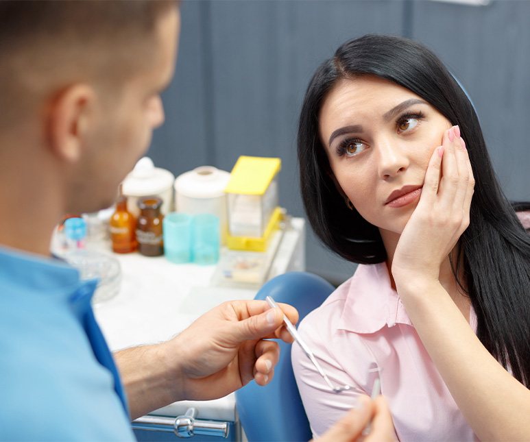 Patient with jaw pain visiting McKinney dentist and holding her cheek