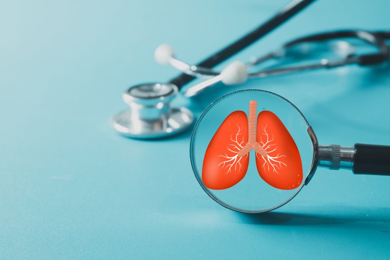 A magnifying glass highlighting a human lung symbol