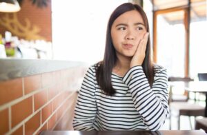 Woman with curious expression holding side of her face.